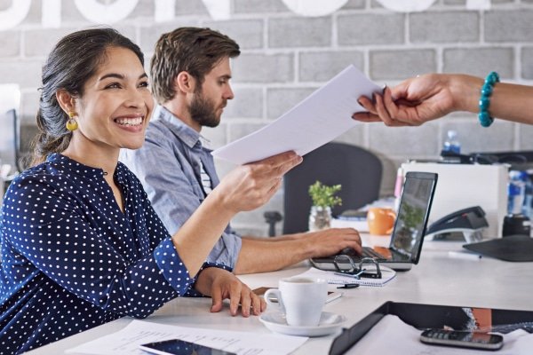 a woman smiling at a man holding a piece of paper