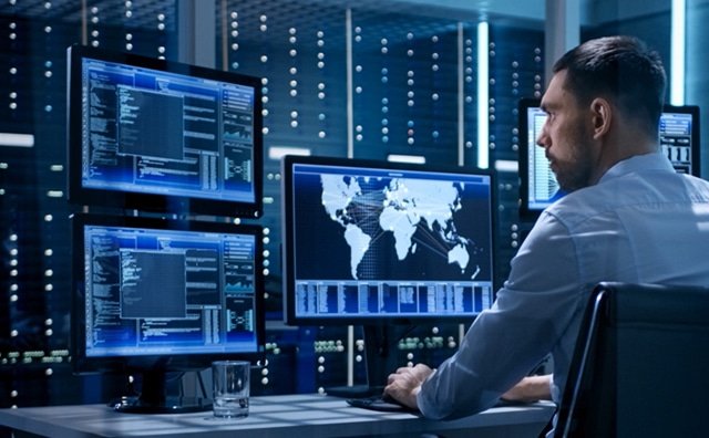 a man sitting in front of several computer screens